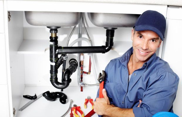 A man holding tools in his hands next to pipes.