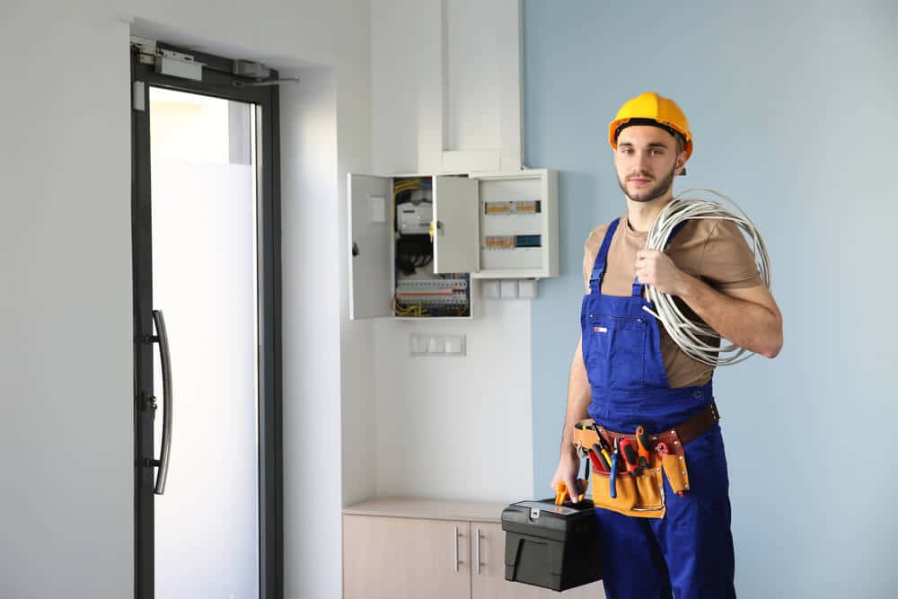 A man in blue overalls holding a tool box.